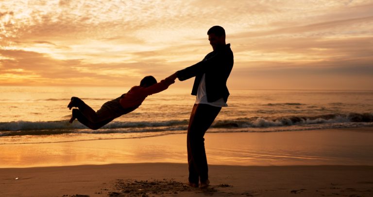 Dad, son and swing on beach at sunset for family bonding, travel for wellness with silhouette. Fath